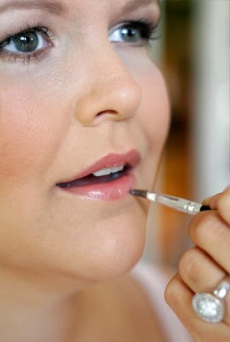 Nahaufnahme: Lippen werden mit einem Lippenpinsel geschminkt