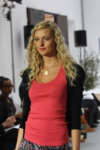 Model mit blonden Locken und rotem Top auf dem Laufsteg