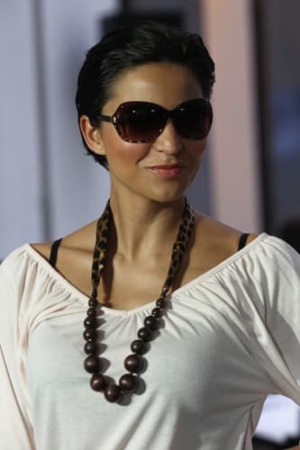 Model mit Kurzhaarschnitt, Sonnenbrille und Holzperlenkette